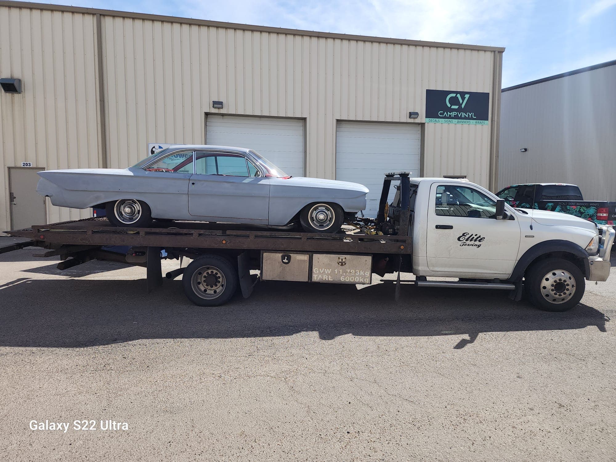 A classic vehicle being transported on a flatbed tow truck