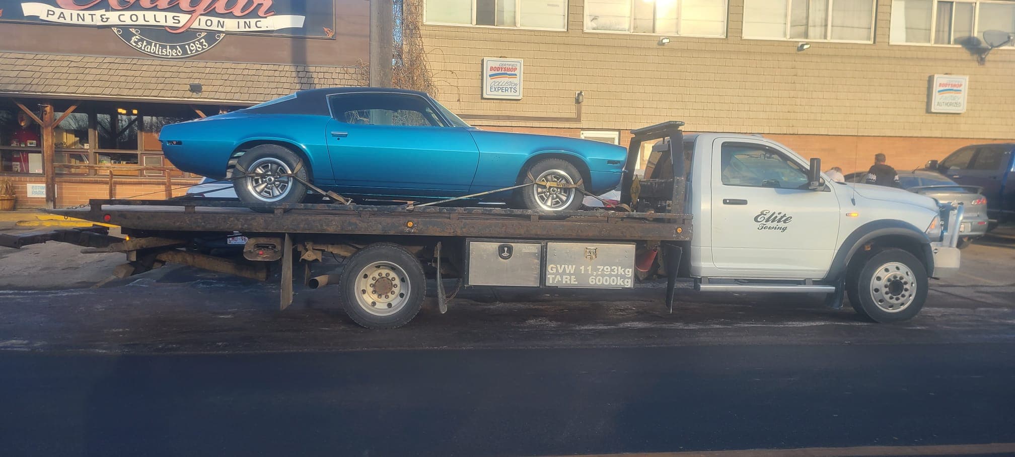 A classic car secured on a flatbed tow truck